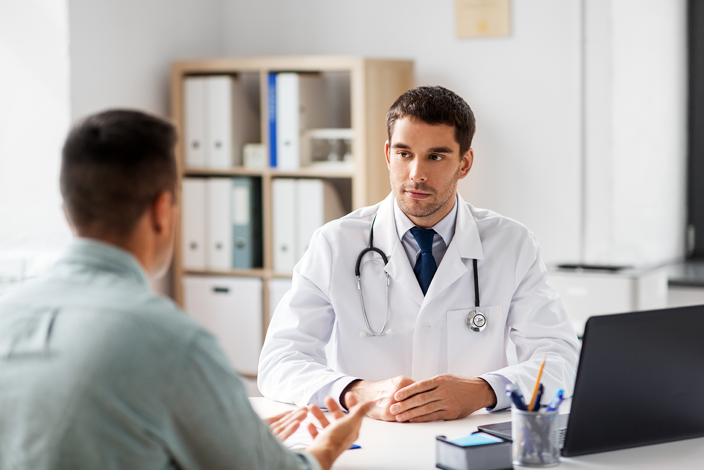 doctor with laptop and male patient at hospital